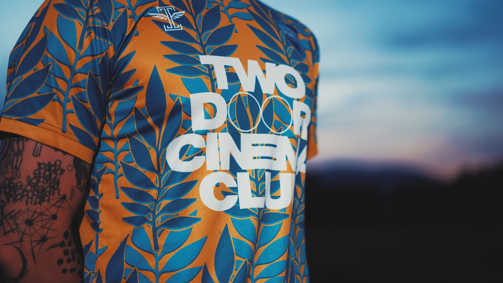 Close-up of the Two Door Cinema Club wordmark and leaf pattern on the shirt